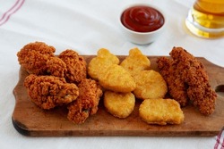 Tasty Fastfood: Chicken Nuggets, Wings and Tenders with Ketchup and Beer, side view.