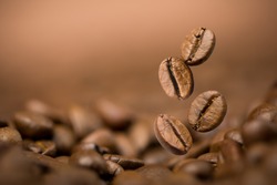 Brown roasted coffee beans falling on pile. Represent breakfast, energy, freshness or great aroma,Flying on dark background with copy space, close-up
