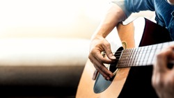 Close up of man's hands playing acoustic guitar. Musical instrument for recreation or hobby passion concept.