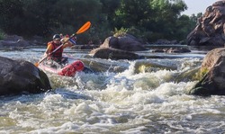 A man rowing inflatable packraft on whitewater of mountain river. Concept: summer extreme water sport, active rest, extreme rafting.