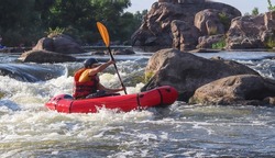 A man rowing inflatable packraft on whitewater of mountain river. Concept: summer extreme water sport, active rest, extreme rafting.