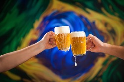 Two people toasting with mugs full of draft beer with stylized Brazilian flag background