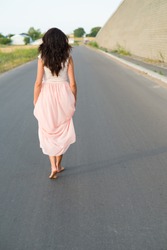 young woman walking barefoot on the road