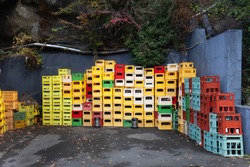 A close up of stacks of plastic multicolor crates containing beer and soft drink bottles in Japan. Old beverage plastic bottle, 