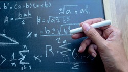 ็ืHand  holding chalk Write mathematical formulas on the blackboard. Concept Difficult problem or Solving mathematical problems.