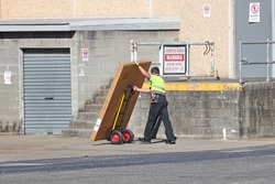 Delivery man making a delivery to a back dock of a shop with a hand truck