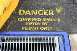 Warning sign painted next to a drain grid on the road