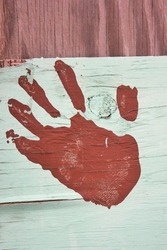 The left hand print of a person in paint on a wooden board.