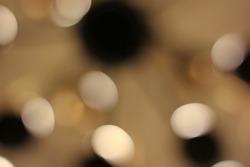 Gorgeous dreamy blurry abstract bokeh of bright gold, white, and black lights floating around the atmosphere.