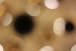 Gorgeous dreamy blurry abstract bokeh of bright gold, white, and black lights floating around the atmosphere.