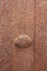 Full frame closeup of a traditional rusted metal sheet with a button rivet.