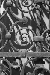 Simple swirl shape decorating a vintage wrought iron metal security gate in a black and white monochrome.