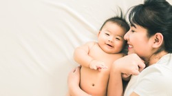 happy family.asian mother playing with her baby in the bedroom.