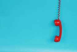 Red telephone receiver over blue background color with copy space