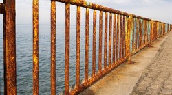 Rusty iron railing, beautiful sea and sky landscape view between rusty railing gap.