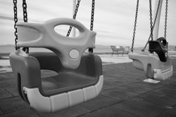 Two empty swings for children in the park. Old black and white photography. Loneliness time concept idea.
