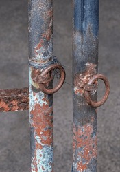 Two isolated rusted steel pipes with metal rings soldered onto them