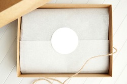 Round sticker mockup, circle white adhesive label in brown gift box.