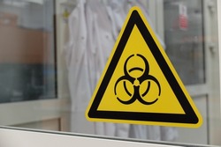 Biological hazard sticker on the doors to cell culture laboratory. Biohazard is a biological substance that poses a threat to the health of living organisms, primarily humans