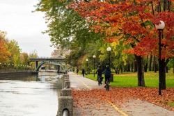 People cycling and walking in Rideau Canal Eastern Pathway. Autumn scenery in Ottawa, Ontario, Canada.