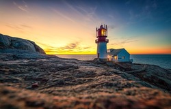 Lighthouse on the shore at dawn. Lighthouse at dawn. Beautiful sunrise over sea coast lighthouse. Lighthouse at dawn landscape