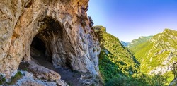 Entrance to a cave in the mountains. Cave in mountain rocks. Mountain rock cave entrance. Cave entrance