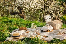 Breakfast picnic with waffles and tea in spring blossom garden on a white tablecloth on a sunny day, cherry blossoms. Outdoor, picnic, brunch, spring mood