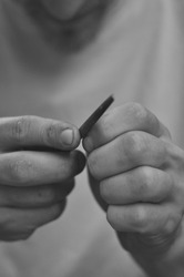 Rock climber is smoothening the skin of his hands with a file. Detail shot of his hands in Black and white.