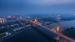 High angle view of the suspension bridges and highway interchange over the Chao Phraya River at dusk, illuminated lights trails on the bridge. Thailand. Long exposure. Selective focus.