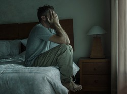Attractive depressed and upset man at home bedroom . dramatic lifestyle portrait of 30s to 40s handsome guy sitting sad on bed feeling worried and desperate suffering depression problem 