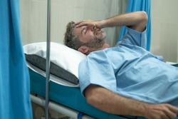 scared and worried man in pain at hospital room - attractive injured man lying on bed suffering painful problem feeling sick and stressed after suffering accident or serious disease 