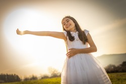 Cute little girl in white first communion dress enjoying the sun