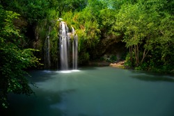 Waterfall and a beautiful lagoon lake for relaxing in the summer forest.