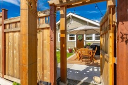 backyard entry gate looking into a sunny cottage style bungalow with patio furniture