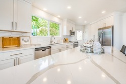 clean white kitchen with marble granite counter tops bright cabinets black bar stools dining table