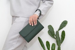green clutch in the hands of a woman in a light gray suit