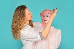 glamorous doctor makes plastic surgery on the face of a mannequin. turquoise background