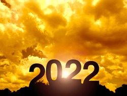 Happy New year 2022 with large silhouette letters on the mountain with beautiful sunset light, sunlight, golden sky and clouds for success concept. Welcome Merry Christmas and Happy New Year in 2022.