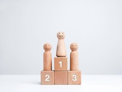 Business competition winner. Smiling female standing on the winner podium on the first award, wooden figure on wood cube block on white background. Women power, goals, success, and leadership concept.