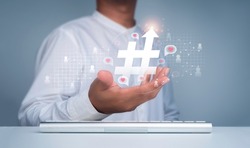 Hashtag concept.  Hashtag icon with arrow up in man's hand and people symbol with heart, love in speech bubbles floating on the social network web. Trendy, viral post and media tag marketing.