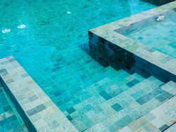 Swimming pool steps with clear water surface background, nobody. Abstract pool texture, underwater pattern blue background with grid tiles, no people. Overhead view. Summer background.