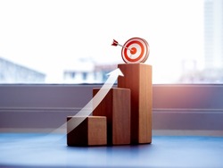 Shining rise up arrow shoot up towards the goal, 3d target icon on the top of wooden cube blocks, bar graph chart steps, business growth process, technology trend, economic improvement concepts.