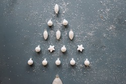 Beautiful Christmas tree shaped out of white festive ornaments on the old rustic grey background, dusted with fake snow