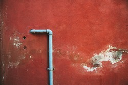 red damaged old wall with a pipe in the middle
