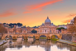 cityscape and panoramic view of old bridge with warm sunset sky water reflections and dome of St. Peters cathedral church with old buildings and architecture in Rome, Italy