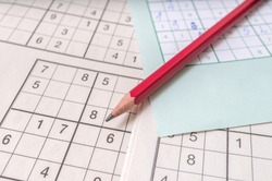 Close view on pencil on sudoku crosswords. Popular game with numbers.