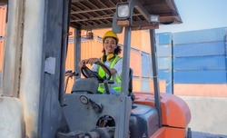 Female foreman is driving heavy lifting forklift at shipping container yard. Smiling African American industrial engineer employee drives reach stacker truck at cargo warehouse port. Woman driver. 