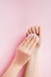 Hand care concept. Young woman remove nail polish on a pink background. Place for text.