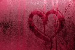 Heart painted on misted glass. Valentines day, love symbol on frozen glass in winter. Selective focus. Color of the year 2023 - Viva Magenta