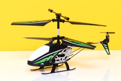 Closeup of a little remote controlled toy helicopter on a bright table against yellow background. Macro photograph of RC helicopter.